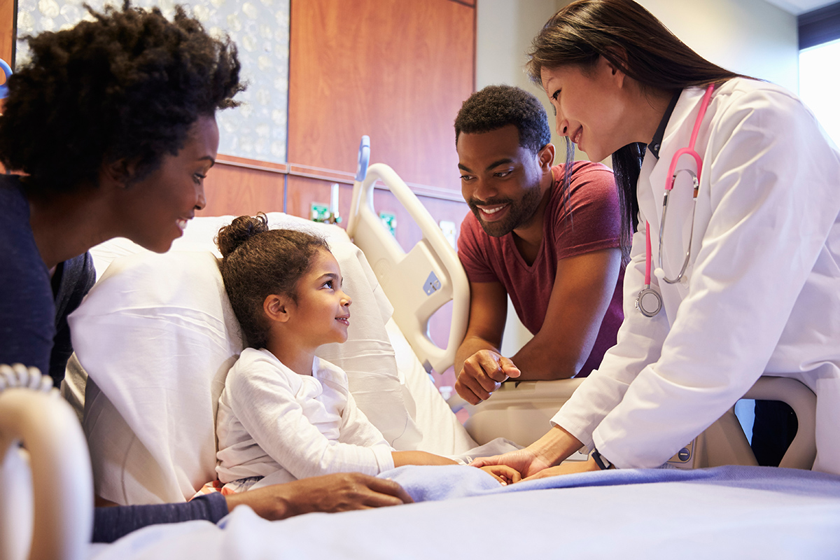 Female doctor with child and family in hospital room