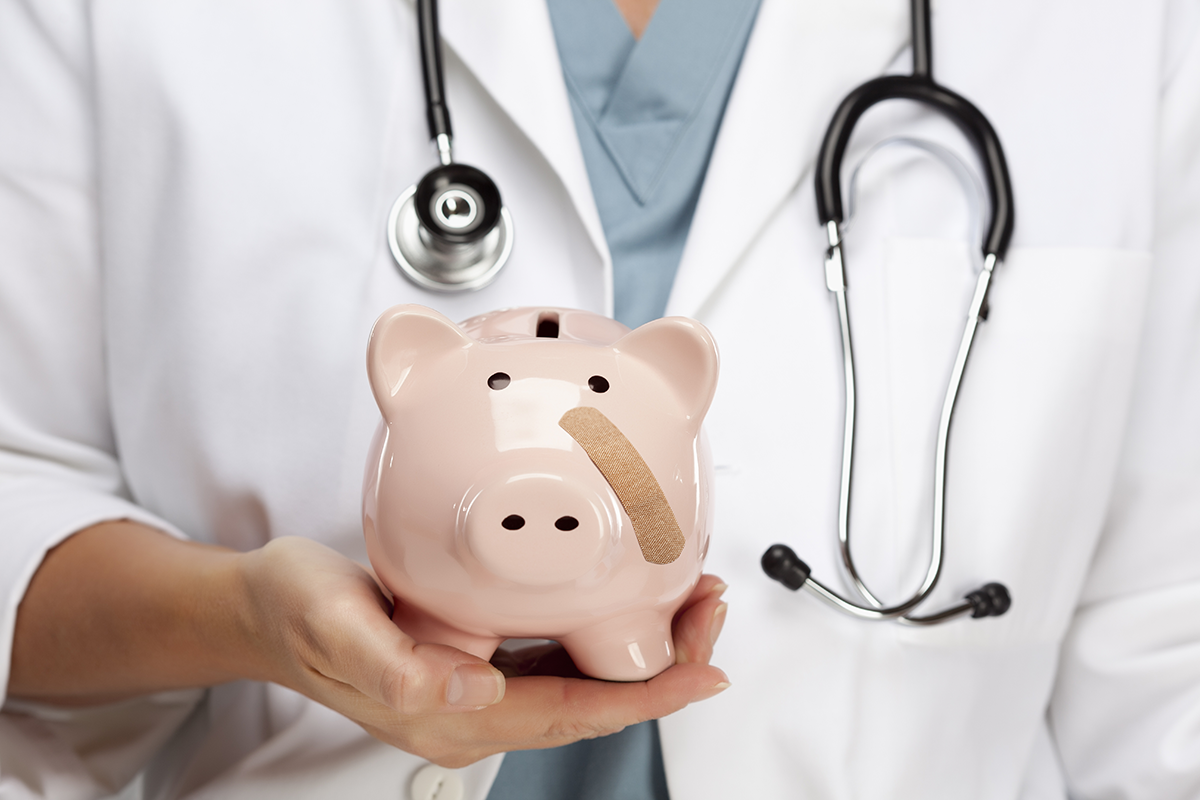 doctor holding a piggy bank with a band aid on it's cheek